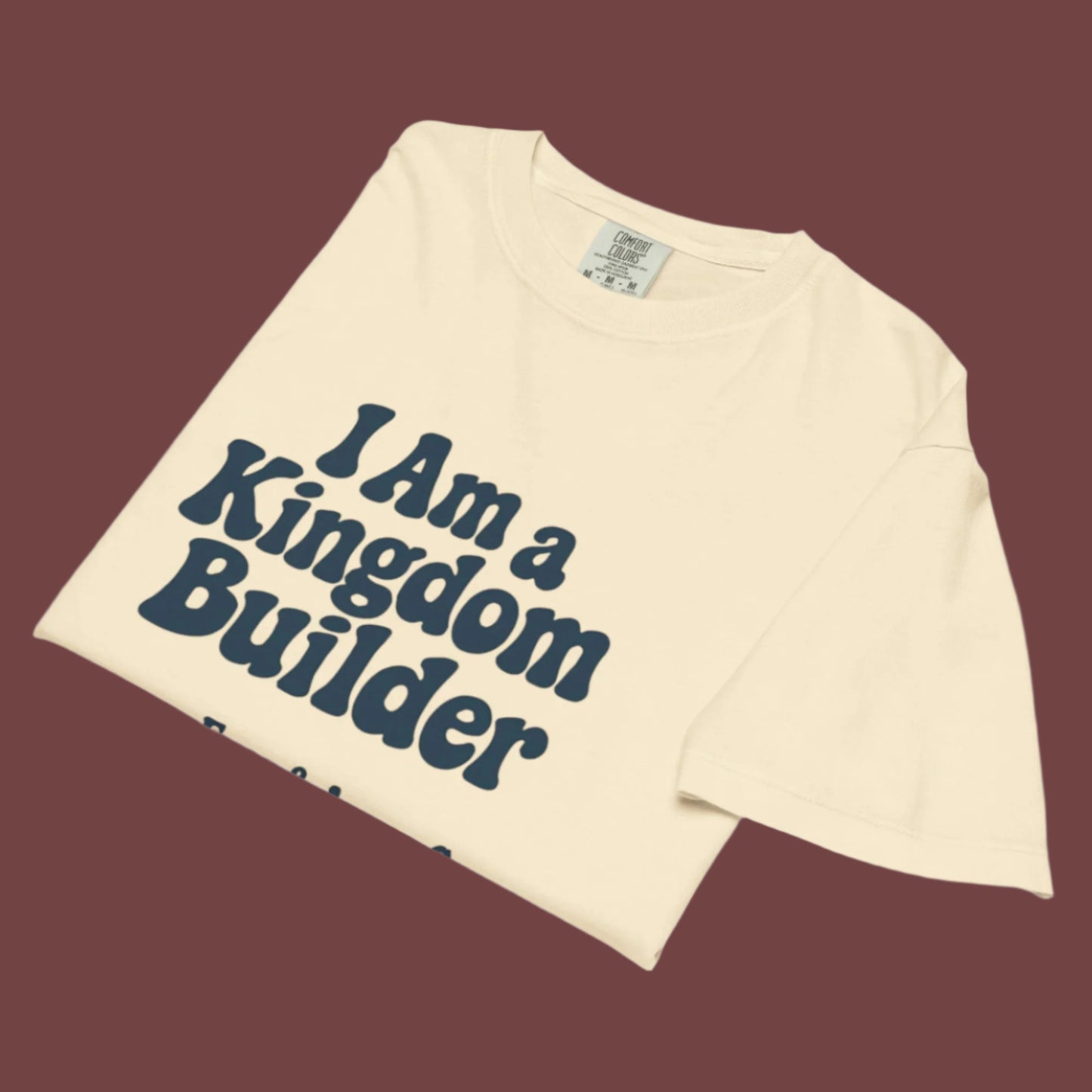 Beige t-shirt with 'I Am a Kingdom Builder' text on a brown background