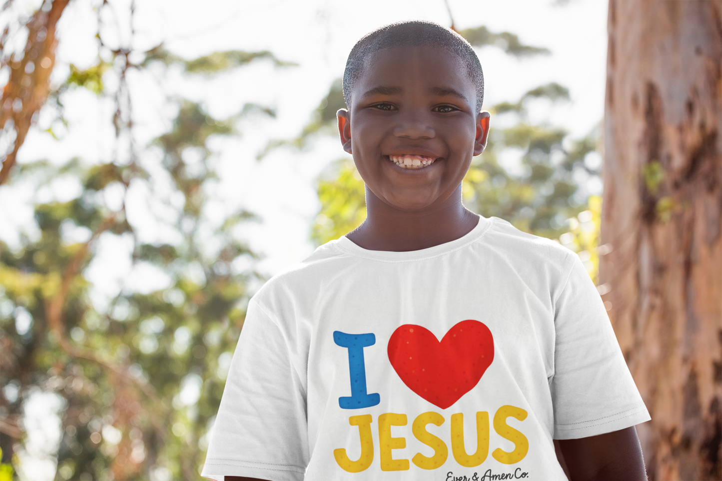 Child wearing a 'I ❤️ JESUS' t-shirt with a blurred natural background